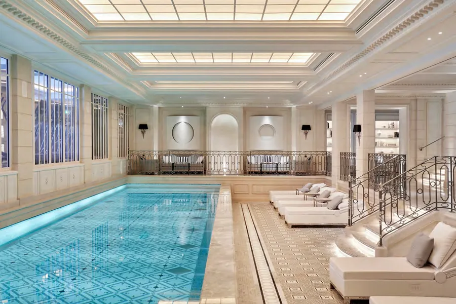 La piscine intérieure du Four Seasons George V, sous une verrière, bordée de transats.